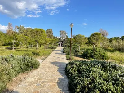a path in a park with a light pole at Kavouri Retreat, Only pines hide the sea in Athens
