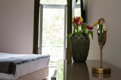 a vase with flowers on a table next to a bed at Nine Athens Hotel in Athens