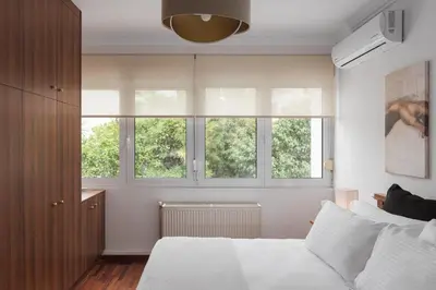 a bedroom with a white bed and three windows at Athenian Secret Glyfada in Athens