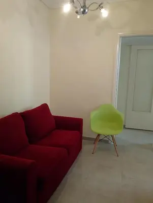 a living room with a red couch and a green chair at Kipseli house in Athens