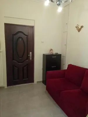 a living room with a red couch and a wooden door at Kipseli house in Athens