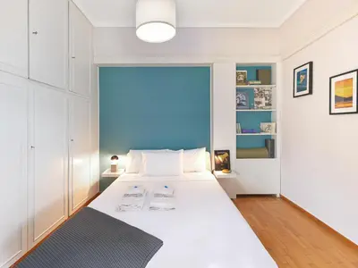 a bedroom with a white bed with a blue wall at Central Pagrati Apartment with Park View Balcony - opp Pangrati Grove in Athens