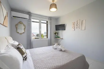 a white bedroom with a bed and a window at Μercy suit in Piraeus