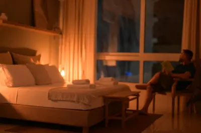 a woman sitting in a chair reading a book in a bedroom at Athens Host - Harmony in Athens