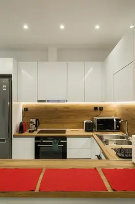 a kitchen with white cabinets and a red rug at 2 br cozy stylish apartment in Athens