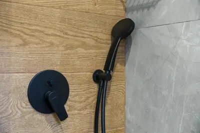 a black shower head on top of a wooden floor at 2 br cozy stylish apartment in Athens