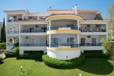 a large white building with blue balconies at Anthilia's House in Porto Rafti