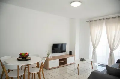 a white living room with a table and a tv at Anthilia's House in Porto Rafti
