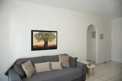 a living room with a gray couch with a tree on the wall at Anthilia's House in Porto Rafti