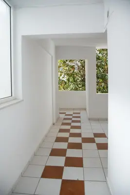 an empty room with a checkered floor and two windows at Anthilia's House in Porto Rafti