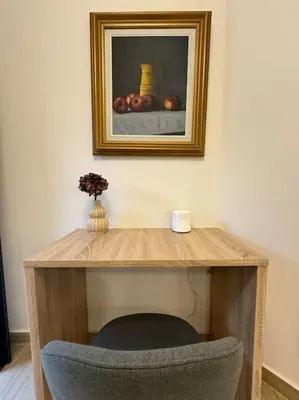 a wooden table with a chair and a picture on the wall at Quiet Studio With Free Parking in Athens