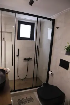 a bathroom with a shower with a toilet and a window at Villa Achilleas by the sea in Anavissos