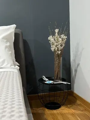 a vase of flowers on a table next to a bed at Marina Zeas Seaview House-MarinaQ in Piraeus
