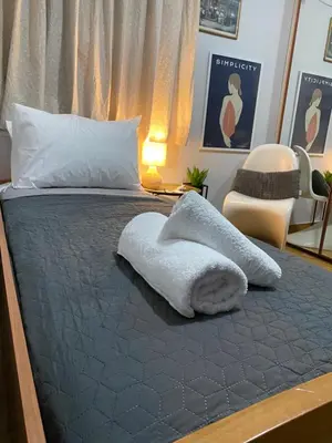 a bed with a white blanket on top of it at Marina Zeas Seaview House-MarinaQ in Piraeus