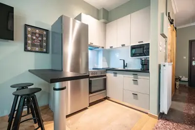 a kitchen with white cabinets and a stainless steel refrigerator at Kipseli 2 prsn studio by MPS in Athens