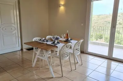 a dining room with a table and white chairs at Keratea Hillside House in Keratea