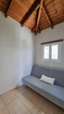 a blue couch in a room with a window at Keratea Hillside House in Keratea