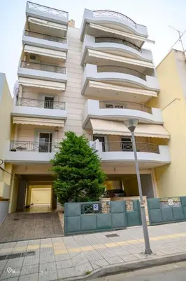 a tall white apartment building with a tree in front of it at Thyme Out - Modern Apartment in Egaleo-Athens in Athens