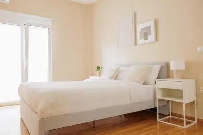 a white bedroom with a large bed with white sheets at Modern 2BDR Apt - 2' to Metro - Direct to Acropolis in Athens