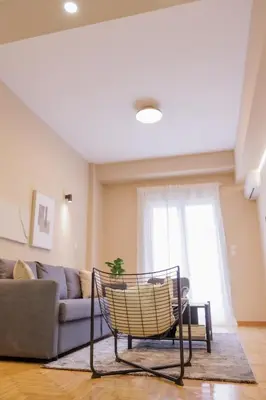 a living room with a chair in front of a couch at Modern 2BDR Apt - 2' to Metro - Direct to Acropolis in Athens