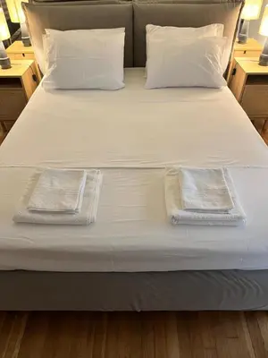 a bed with white sheets and two towels on it at Quiet Apartment with Garden View in Kolonaki in Athens