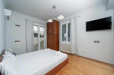 a white bedroom with a bed and a flat screen tv at Φ Villa by A&D Properties in Porto Rafti