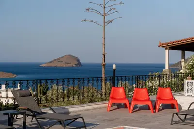 a group of four chairs sitting next to the ocean at Φ Villa by A&D Properties in Porto Rafti