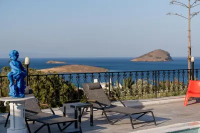 a statue and chairs on a balcony with the ocean at Φ Villa by A&D Properties in Porto Rafti