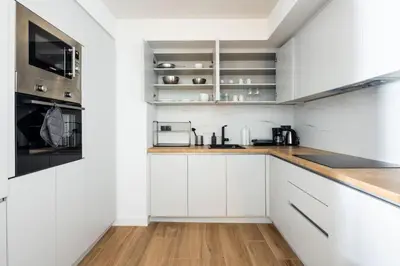 a white kitchen with white cabinets and wooden floors at Nostalgia 1-Bedroom Apartment in Athens in Athens