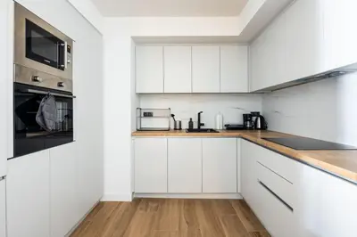 a white kitchen with white cabinets and a wooden floor at Nostalgia 1-Bedroom Apartment in Athens in Athens
