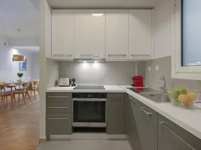 a kitchen with white cabinets and a sink and a table at Marnis10 5th Right in Athens