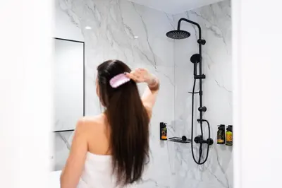 a woman brushing her hair in a shower at Bueno Apartments by Athens Prime Hotels in Athens