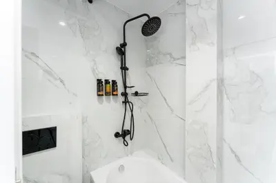 a bathroom with a shower with white marble walls at Bueno Apartments by Athens Prime Hotels in Athens