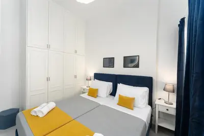 a white bedroom with a bed with yellow pillows at Bueno Apartments by Athens Prime Hotels in Athens