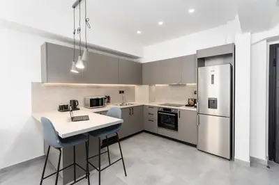 a kitchen with a refrigerator and a table and chairs at Bueno Apartments by Athens Prime Hotels in Athens