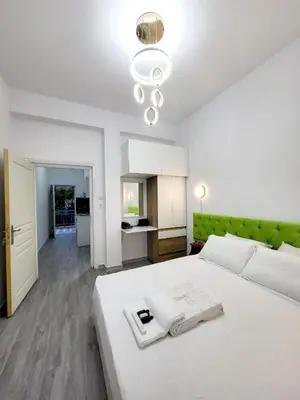a bedroom with a large white bed with a green headboard at AHAMED GREEK SMPCO in Athens