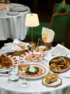 a table with plates of food and glasses of wine at The Margi in Athens