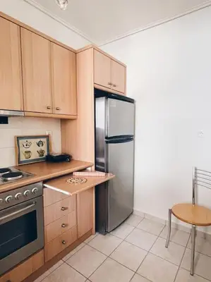 a kitchen with wooden cabinets and a stainless steel refrigerator at CS Central Apartment in Athens