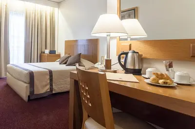 a hotel room with a bed and a desk with a table with a bed gmaxwell at Ilissos in Athens