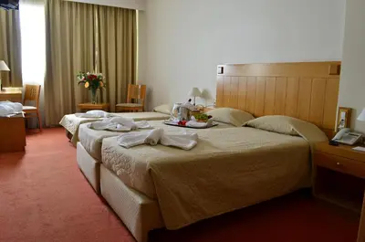 a hotel room with three beds with towels on them at Ilissos in Athens
