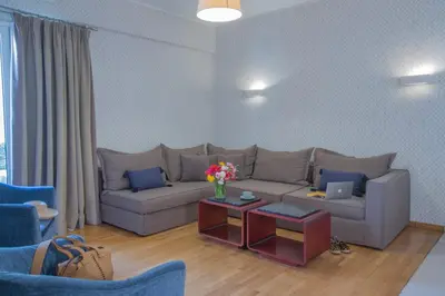 a living room with a couch and a table with flowers at Delice Hotel - Family Apartments in Athens