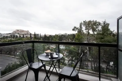a table and two chairs on a balcony with a view at Acropolis Amazing View: One-Bedroom Gem in Athens