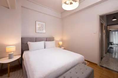 a bedroom with a large white bed and a window at Acropolis Amazing View: One-Bedroom Gem in Athens