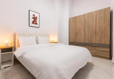 a white bedroom with a large bed and a cabinet at LIV - Modern Spacious Apartment in Gazi in Athens