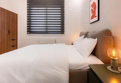 a bedroom with a white bed and a table with a lamp at LIV - Modern Spacious Apartment in Gazi in Athens
