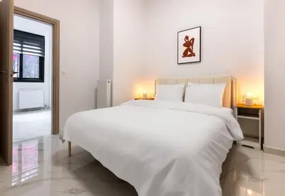 a white bedroom with a large white bed with two lamps at LIV - Modern Spacious Apartment in Gazi in Athens