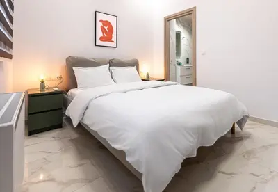 a white bedroom with a large bed and a mirror at LIV - Modern Spacious Apartment in Gazi in Athens