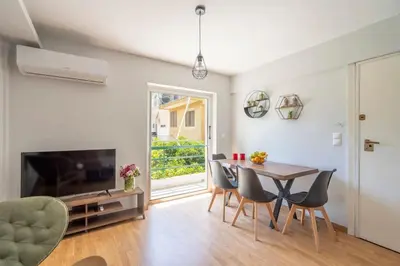 a living room with a table and chairs and a television at Tranquil Voula Getaway, A Calm Retreat in Voula in Athens