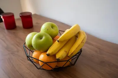 a bowl of bananas apples and oranges on a table at Tranquil Voula Getaway, A Calm Retreat in Voula in Athens