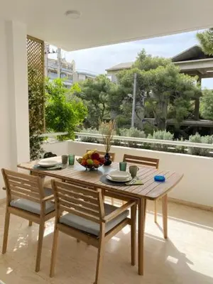 a wooden table and chairs in a room with a balcony at Vouliagmeni Seaside Luxury Home in Athens